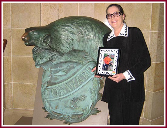 Eilene Ribbens of the Wisconsin Puppy Mill Project stands by a statue bearing the WI State motto "FORWARD" in the State Capitol in Madison as WI Act 90 was signed into law.